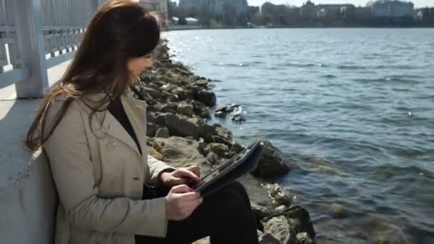 Mujer en la playa, la lectura de la tableta de ordenador y muestra como — Vídeo de stock