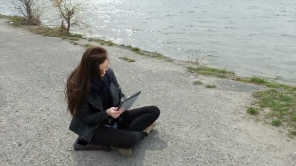 Улыбающаяся женщина на пляже использует свои планшетные шоу, как — стоковое видео