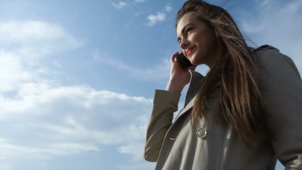 Jong meisje met telefoon tegen blauwe hemel — Stockvideo