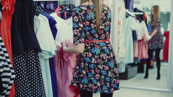 Beautiful girl trying dress near mirror on room background — Stock Video