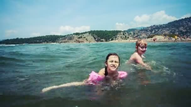 Zwei kleine Mädchen im Urlaub schwimmen in einem flachen Wasser am tropischen Ozean — Stockvideo