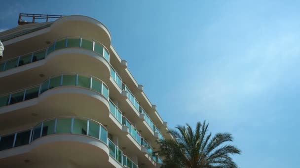 Белое жилое здание и пальма против голубого неба — стоковое видео