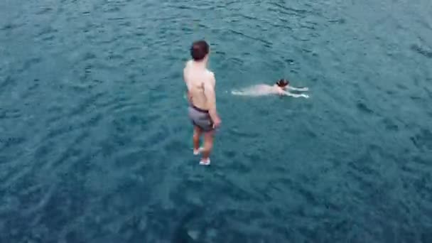 Een man springen in turquoise water van de lagune. — Stockvideo