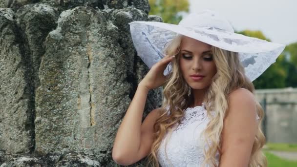 Modesto sposa in un bianco cappello guardando fotocamera — Video Stock