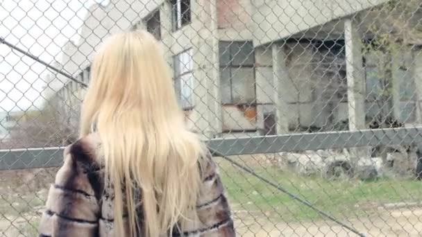 Κομψό ξανθιά κοπέλα με φωτεινό μακιγιάζ, σε ένα πολυτελές γούνινο παλτό απότομα γυρίζει γύρω και να πηγαίνει στην πλευρά της κάμερας — Αρχείο Βίντεο