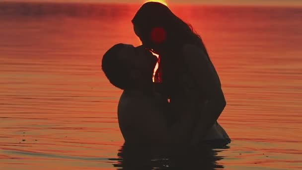 Романтический поцелуй в воде на фоне заката — стоковое видео