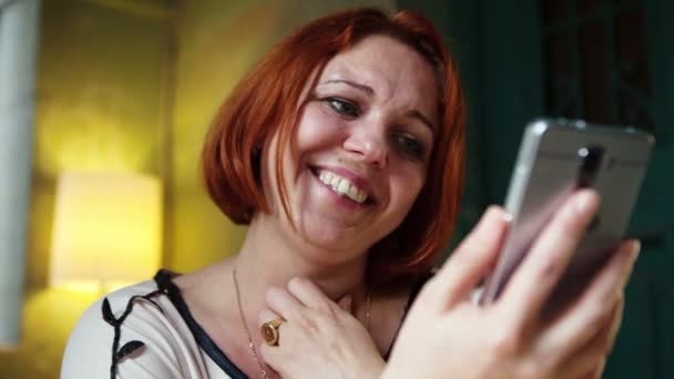 Gelukkig volwassen vrouw foto's weergeven op uw telefoon en gelukkig lachen — Stockvideo