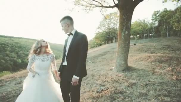 Bella sposa coppia si bacia sulla collina e tramonto sfondo abbagliamento — Video Stock