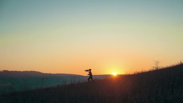 Silhouet jongen spelen met speelgoed vliegtuig en een stijgende zon — Stockvideo