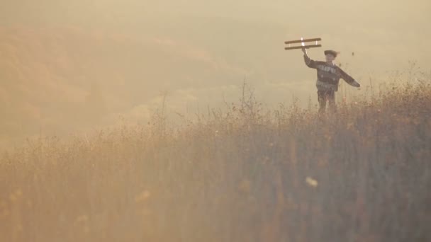 Joven feliz corriendo con avión de madera en la colina de otoño — Vídeo de stock