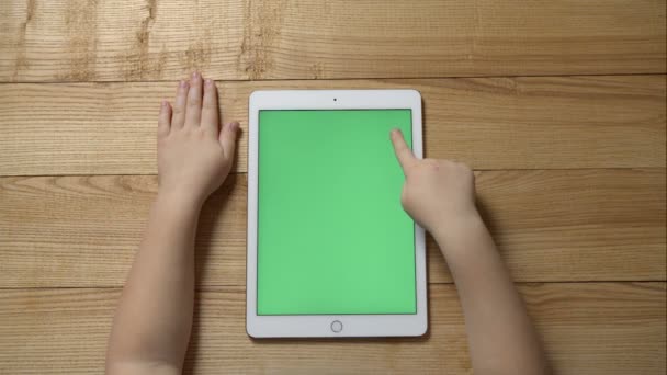 Young girl using a tablet sitting on a wooden table. Top view — Stock Video