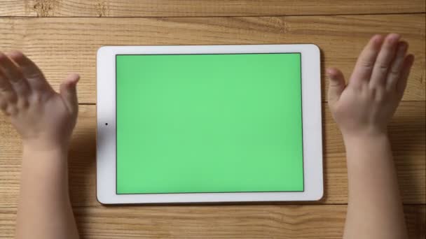 Un petit enfant avec un ordinateur tablette avec un écran vert sur une table en bois — Video