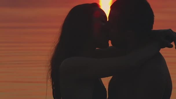 Jovem casal beijando ao pôr do sol na água — Vídeo de Stock
