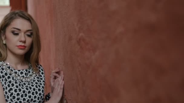 Красивая молодая женщина в вечернем платье у стены — стоковое видео