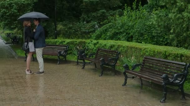 Junges Paar mit Regenschirm auf der Straße der Stadt — Stockvideo