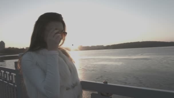 Hermosa joven en la ciudad junto al lago con gafas — Vídeos de Stock