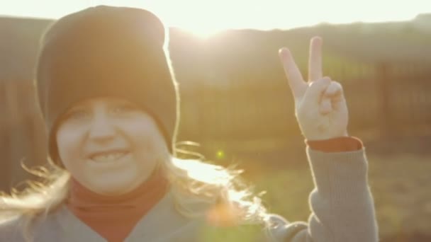 La niña muestra un símbolo de paz. Día soleado brillante de la primavera . — Vídeos de Stock