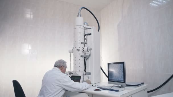 Científico senior que investiga en equipo de laboratorio microscopio electrónico . — Vídeo de stock