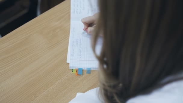 Un estudiante toma notas en su cuaderno durante las conferencias — Vídeo de stock