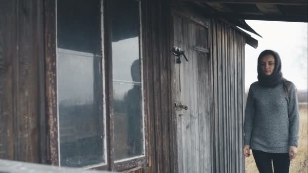 Женщина в теплом шарфе вокруг одинокого старого дома. Видеозапись В. . — стоковое видео