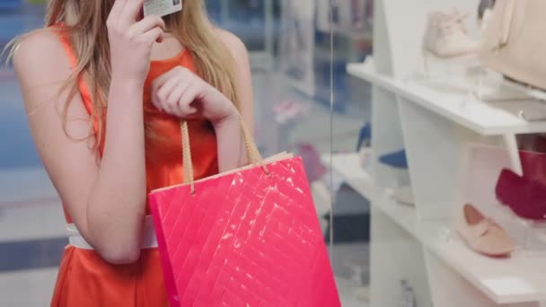 Schöne Mädchen am Schaufenster mit Kreditkarte und treffen die Entscheidung, die Waren zu kaufen und ist im Geschäft — Stockvideo
