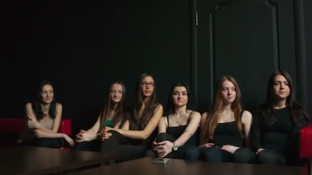 Grupo de meninas em um quarto preto sentado à mesa — Vídeo de Stock