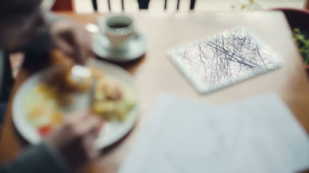 Mesa con una tableta y documentos - Desayuno joven empresario — Vídeo de stock