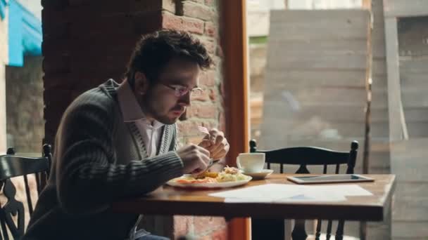 Genç işadamı bir tablet ile çalışan bir restoran yiyor — Stok video