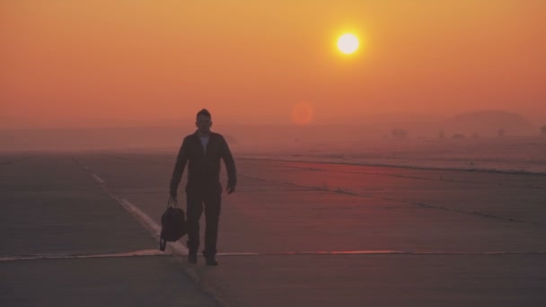 Havaalanı pist üzerinde gündoğumu bir arka plan üzerinde deri ceketli bir adamdır — Stok video