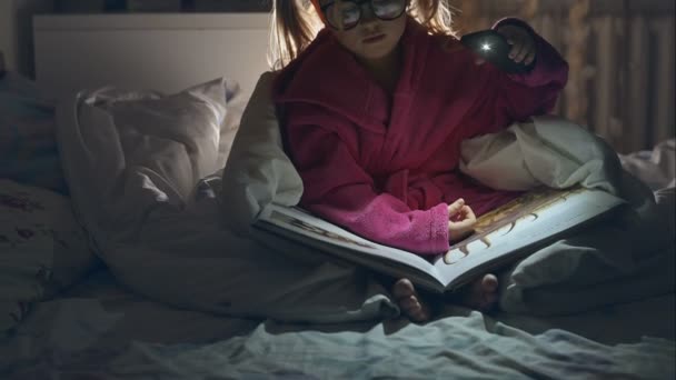 Chica leyendo un libro con lámpara. Grabación de vídeo RAW . — Vídeos de Stock