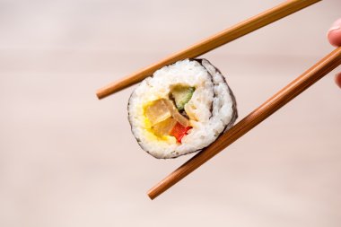 Suşi ekmeğini yemek çubuklarıyla tutarak.