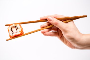 Suşi roll üzerine beyaz izole bambu çubuk ile tutan el
