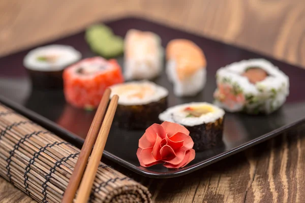 Fresh Japanese tasty sushi roll set with chopsticks on wooden ta — Stock Photo, Image