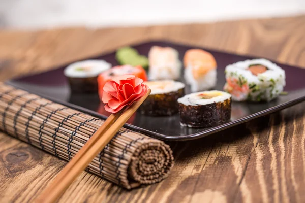 Sushi chopsticks with origami flower on sushi background — Stock Photo, Image