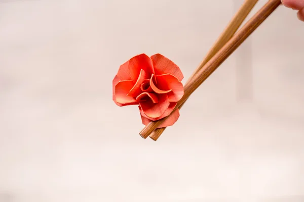 Sushi chopsticks with origami flower on light background