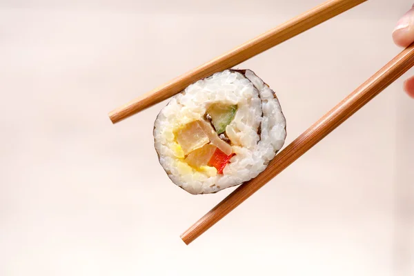 Hand holding sushi roll using chopsticks — Stock Photo, Image