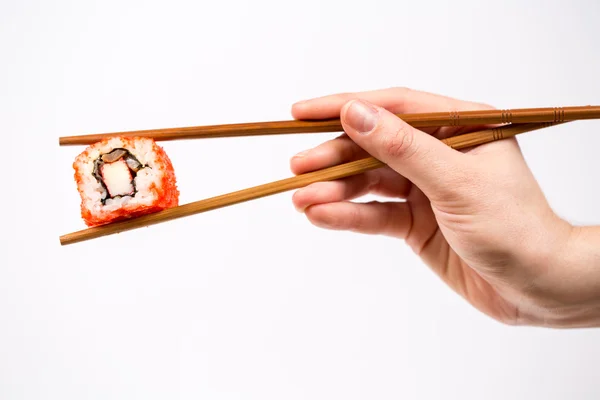 Hand holding Sushi roll with bamboo chopsticks isolated on white — Stock Photo, Image