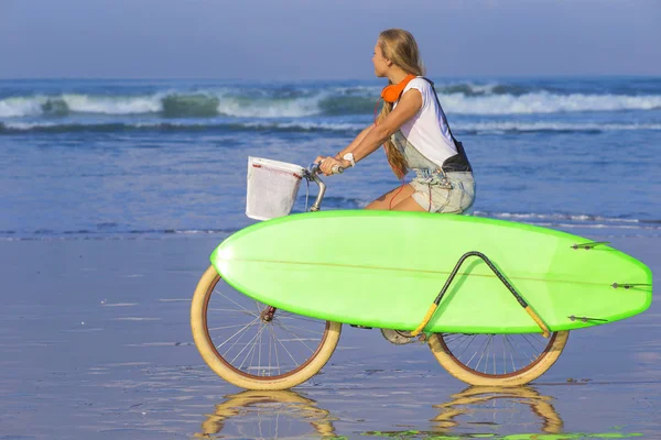 Surfer girl with a bicycle — Stock Photo, Image