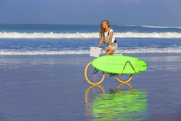 Surfer girl with a bicycle — Stock Photo, Image