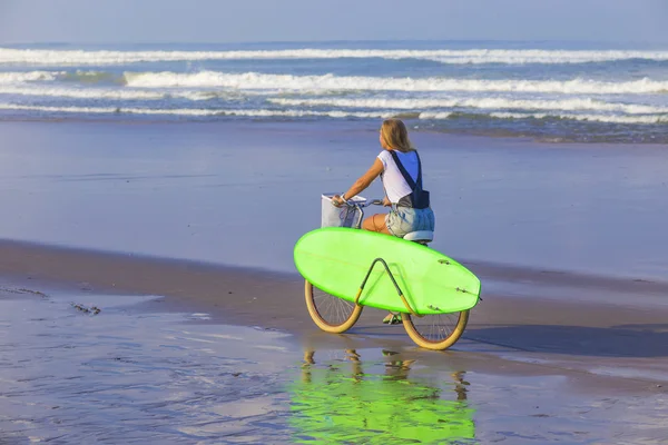 Surfer girl with a bicycle — Stock Photo, Image