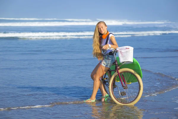 Surfer girl with a bicycle — Stock Photo, Image