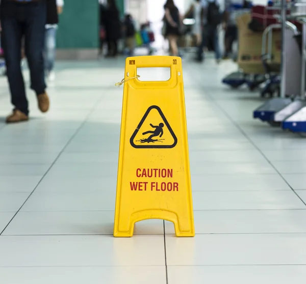 Geel teken dat waarschuwt voor natte vloer. — Stockfoto