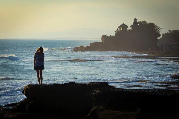 Ung kvinde på havet cpastline med hindu tempel Pura Tanah Lot - Stock-foto