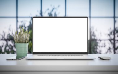 Ofis masasında boş ekranı olan bir laptop. Arkaplanda ağaçlar olan pencere