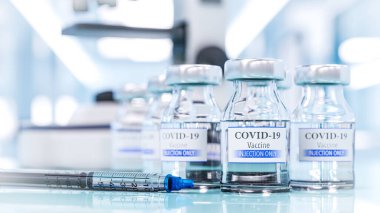 Coronavirus aşısı icat edildi. Hastanedeki mikroskobun arka planında sıvı ve şırınga bulunan bir şişe.