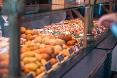 İtalyan hamur işleri ve pizzaları bir fırının cam tezgahının arkasında çeşitli lezzetli seçenekler sunuyor..