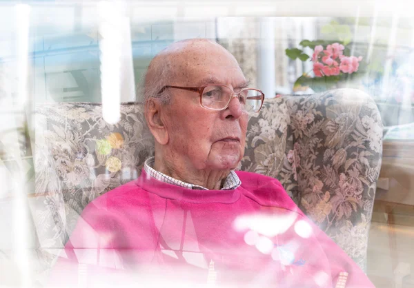 Portrait of 95 years old English man sitting in chair in domestic environment with glass reflection effect. Health and care concept — Stock Photo, Image