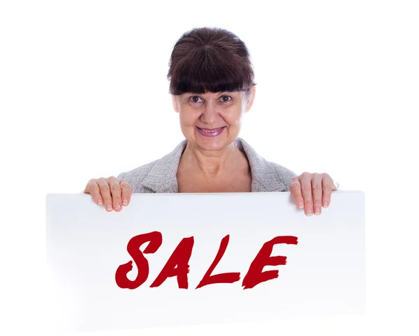 Mature woman leaning on white banner with Sale sing. Portrait against of white background — Stock Photo, Image