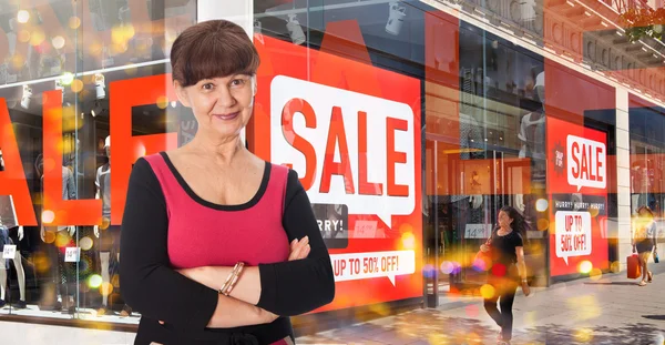 Attractive elderly woman smiling, against of Sale window display — Stock Photo, Image