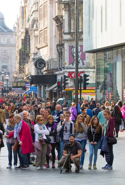 :Spousta lidí, turistů a Londýňané chůze přes Leicester square, slavný destinací Londýn pro noční život, kina, restaurace a bary — Stock fotografie